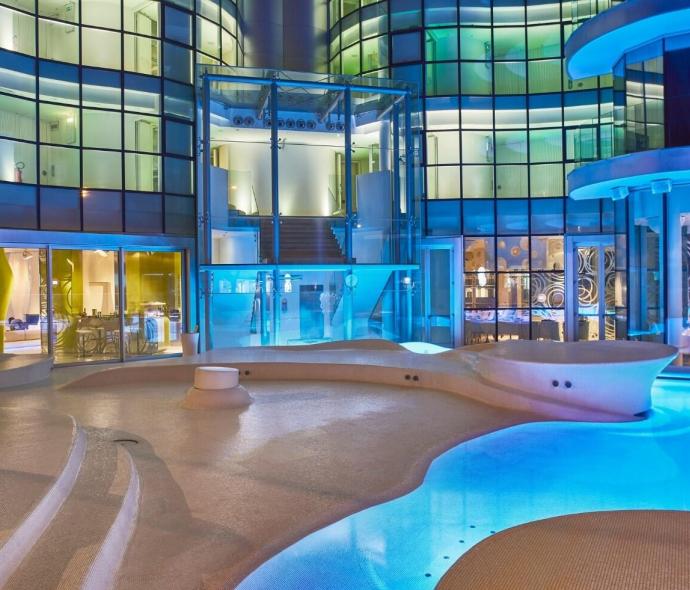 Futuristic illuminated pool with modern glass building.