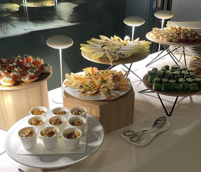 Buffet di finger food gourmet con vari antipasti su tavoli illuminati.