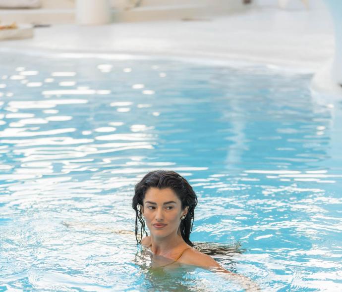 Donna nuota in piscina con acqua limpida.