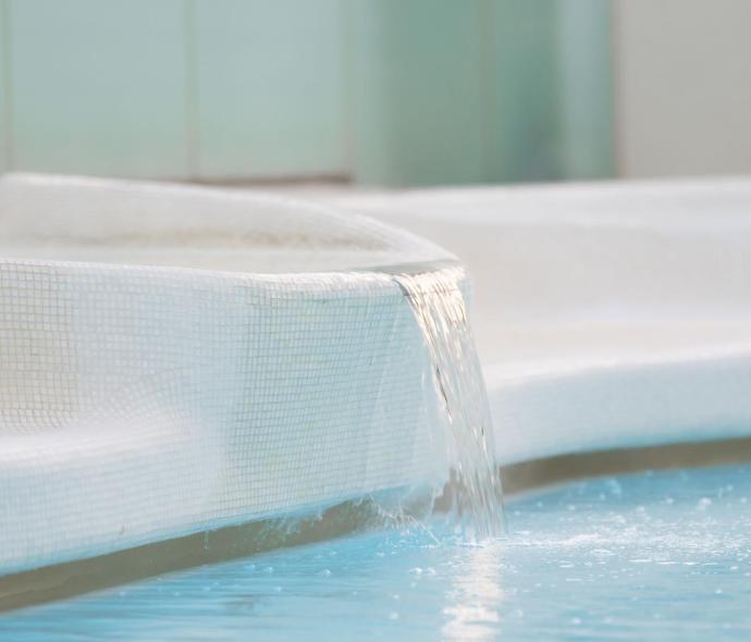 Pool with water cascade in a modern setting.