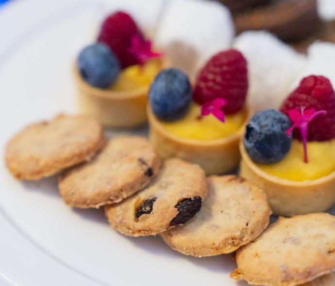 Assorted desserts with berries and cookies on a white plate.