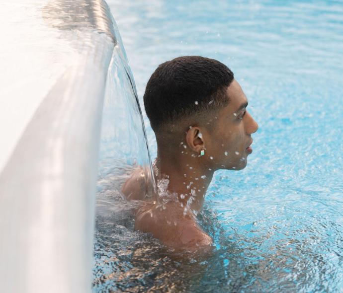 Person im Pool unter einem Wasserfall.