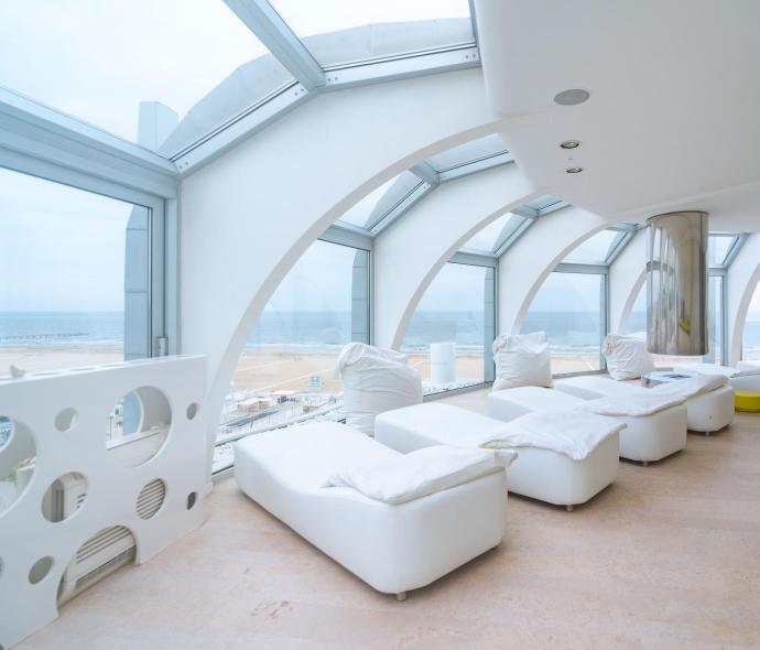 Relaxation room with sea view and white loungers.