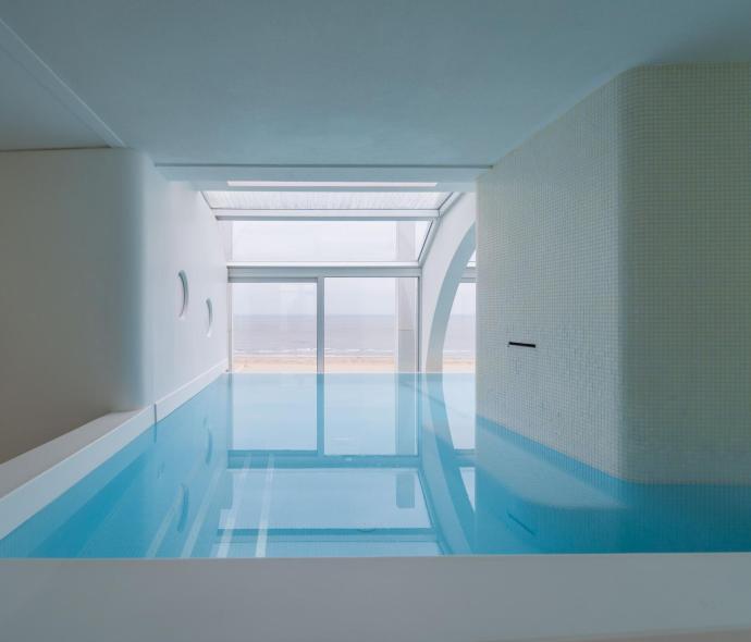 Innenpool mit Meerblick durch große Fenster.