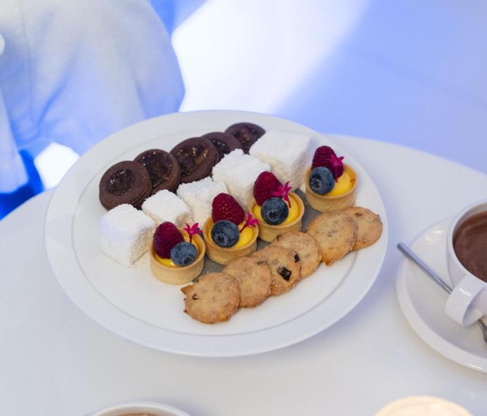 Verschiedene Desserts und heiße Schokolade auf einem Tisch mit Kerze.