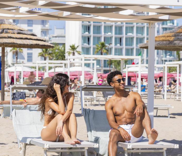 Glückliches Paar sonnt sich auf Strandliegen, sommerliche Stimmung und entspannte Atmosphäre.