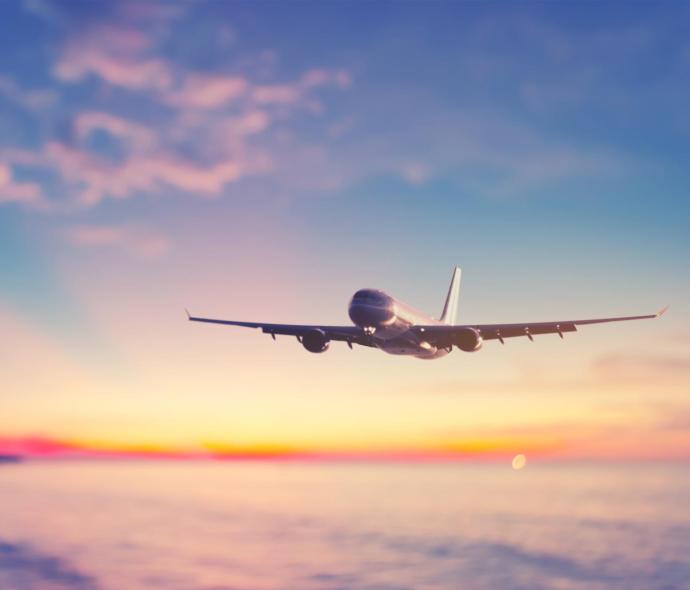 Flugzeug fliegt bei Sonnenuntergang über ruhiges Meer, bunter Himmel berührt.