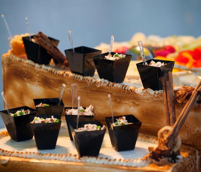 Piccoli bicchieri neri con riso e spezie su tavolo decorato.