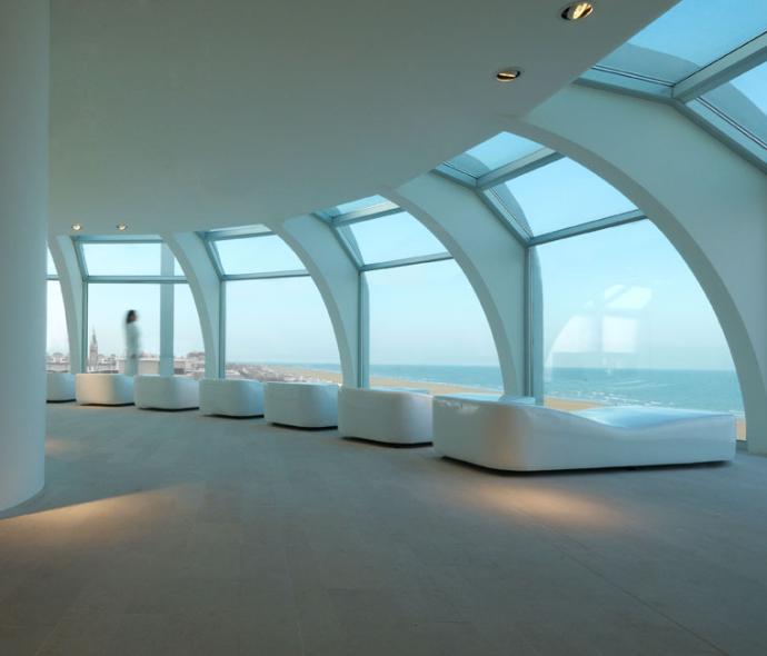 Moderno spazio con vista sul mare, grandi finestre e sedute bianche.