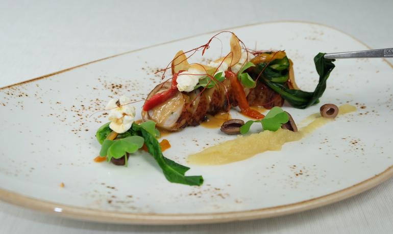 Piatto gourmet con carne, verdure e guarnizioni eleganti.