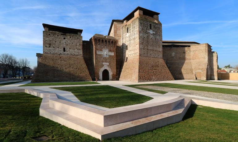 Alte Festung mit Backsteinmauern und grünem Innenhof.