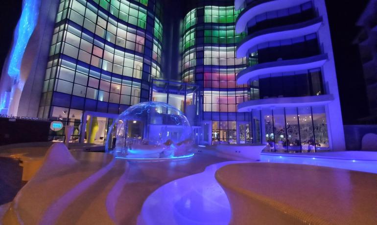 Edificio moderno illuminato di notte con piscina e cupola di vetro.