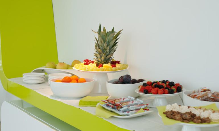 Buffet avec fruits frais, snacks et divers desserts sur une table blanche.