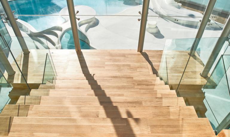 Moderne Holztreppe mit Blick auf blauen Pool und elegantem Design.
