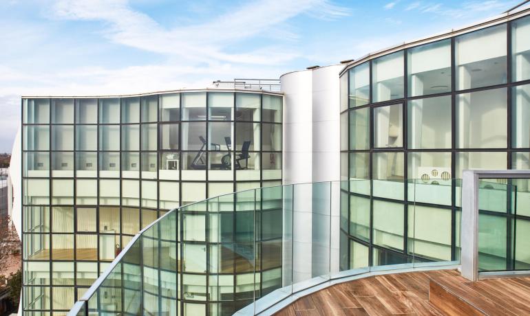 Edificio moderno con ampie vetrate e terrazza in legno.