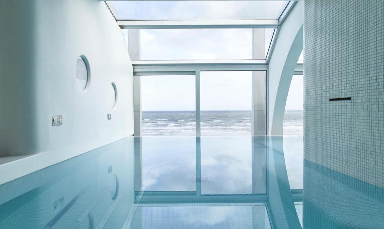 Piscina interna con vista sull'oceano e ampie finestre.