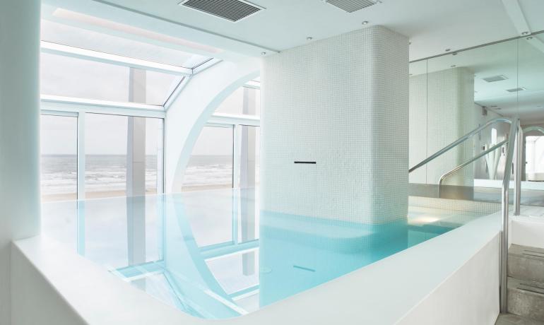 Piscina interna con vista sull'oceano e design moderno e luminoso.