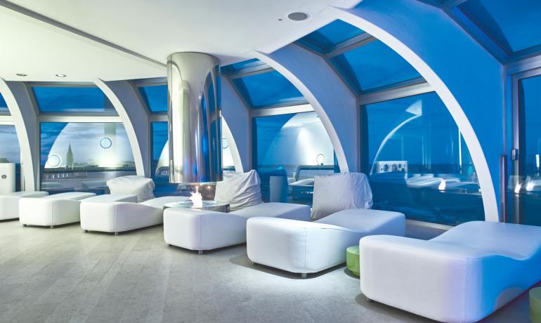 Lounge moderna con divani bianchi e finestre panoramiche.