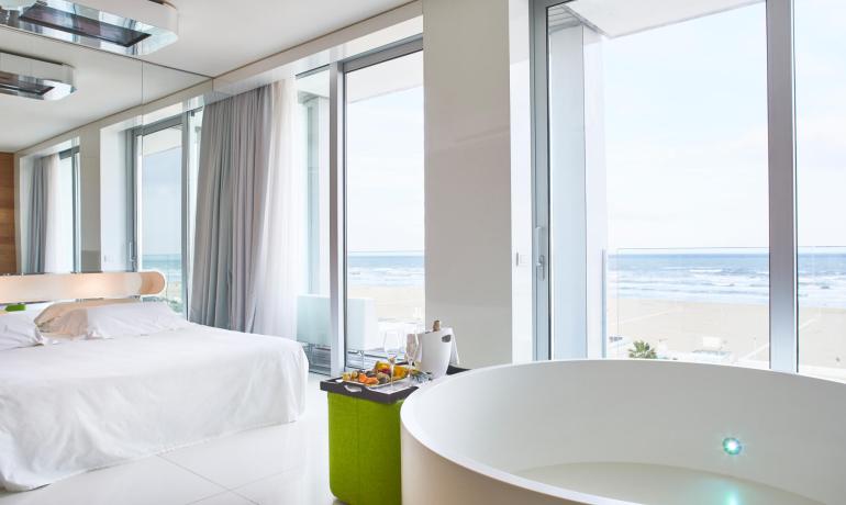 Modern room with sea view, bathtub, and bed.