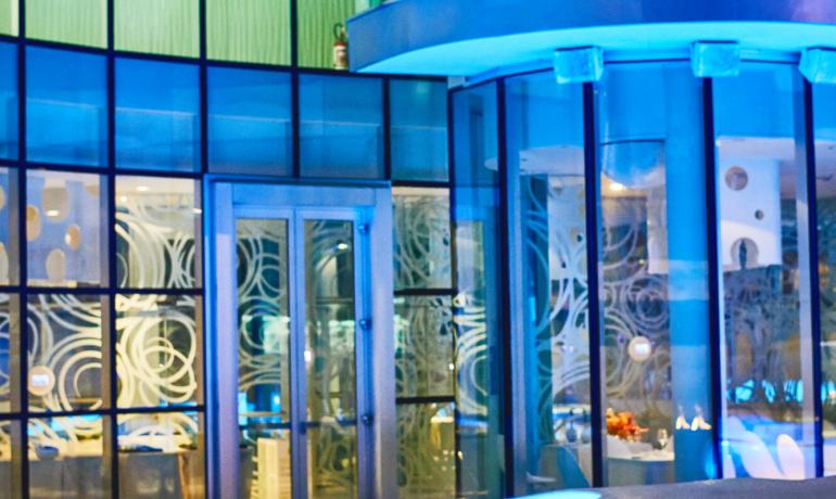 Edificio moderno con luci blu e fiamma decorativa.