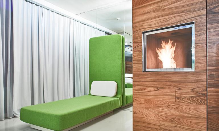 Sala moderna con chaise longue verde e camino.