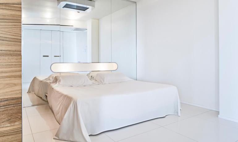 Modernes Zimmer mit Doppelbett und Spiegeln.