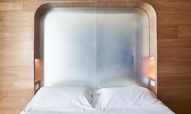 Letto con testiera moderna in legno e illuminazione integrata.