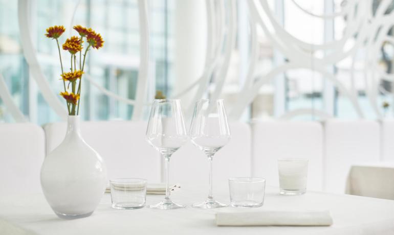 Tavolo elegante con bicchieri, vaso e fiori in un ristorante moderno.