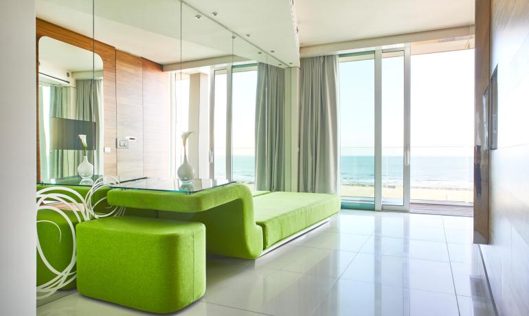 Moderno soggiorno con vista mare e arredamento verde brillante.