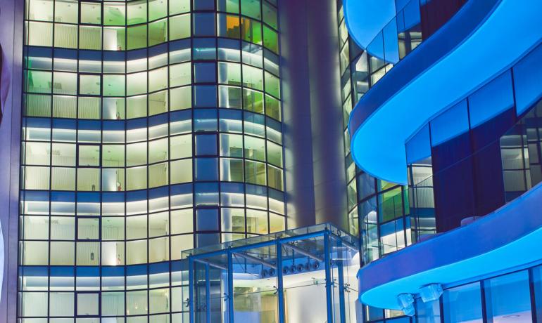 Edificio moderno illuminato di notte con piscina e vetrate curve.