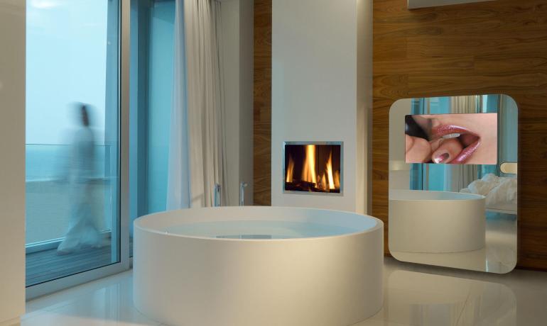 Bagno moderno con vasca, camino e specchio.