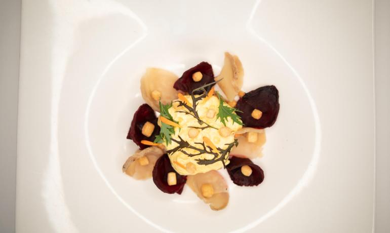 Piatto gourmet con verdure e crema decorativa.