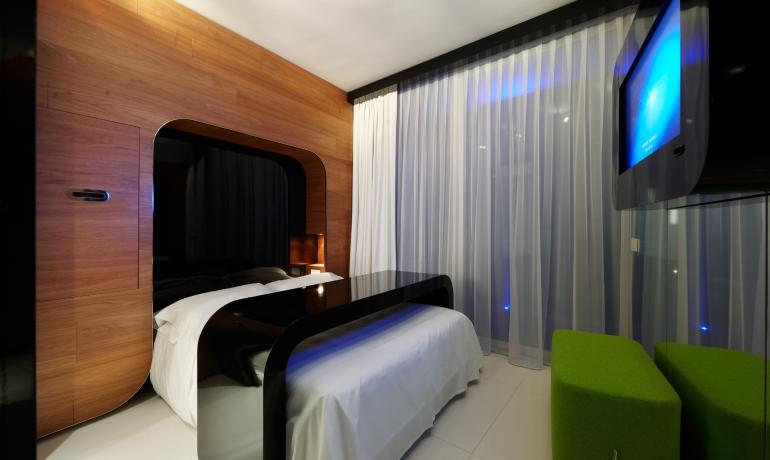 Modern room with bed, TV, and green seats.