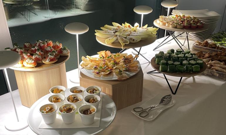Gourmet finger food buffet with various appetizers on illuminated tables.
