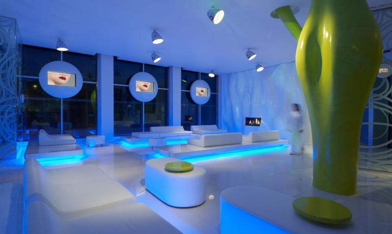 Salon moderne avec éclairage bleu et mobilier blanc.