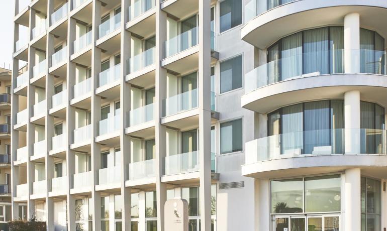 Bâtiment moderne avec balcons courbes et jardin.