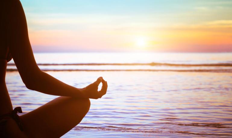 Meditation bei Sonnenuntergang am Meer, Frieden und Gelassenheit.