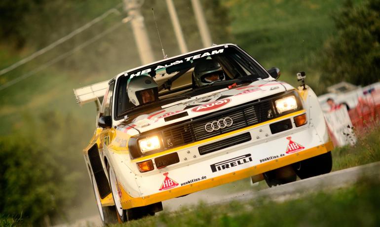 Voiture de rallye Audi en action sur une route en terre.