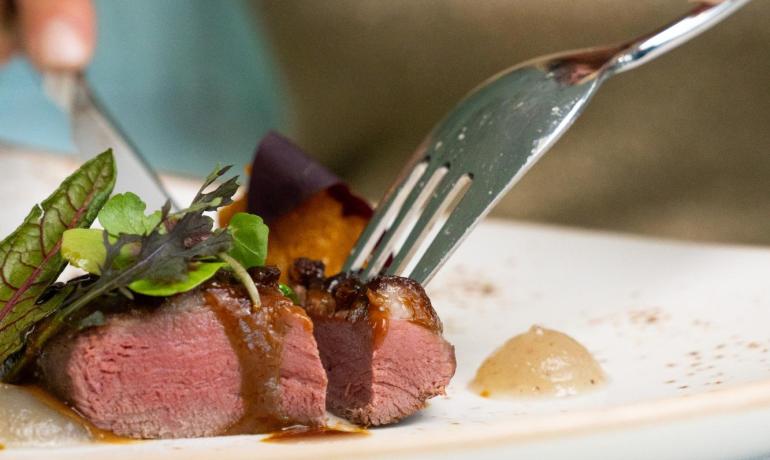 Viande juteuse avec sauce et légumes sur une assiette élégante.