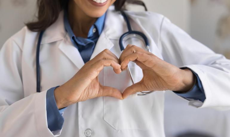Doctor with stethoscope forms a heart with hands.