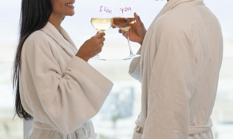 Coppia in accappatoi brinda con calici 'I love you'.
