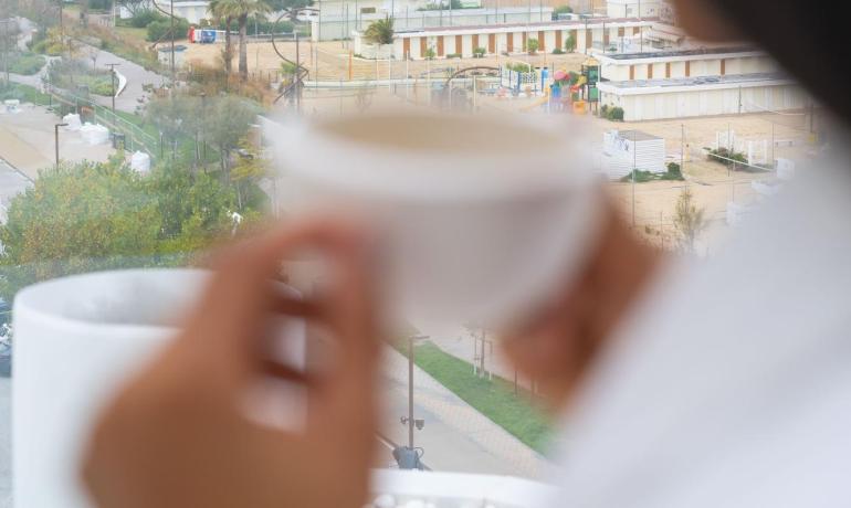 Vue sur la mer avec une tasse de café à la main.