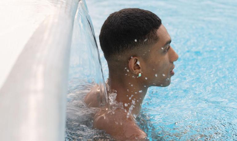 Person in a pool under a waterfall.