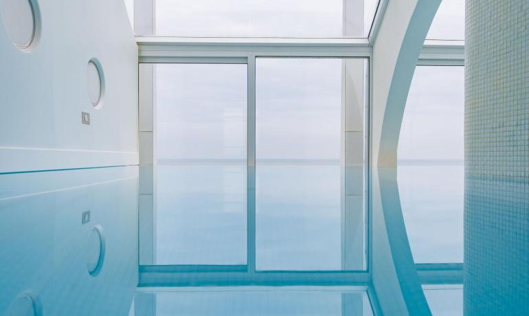 Piscine intérieure moderne avec grandes fenêtres et lumière naturelle.