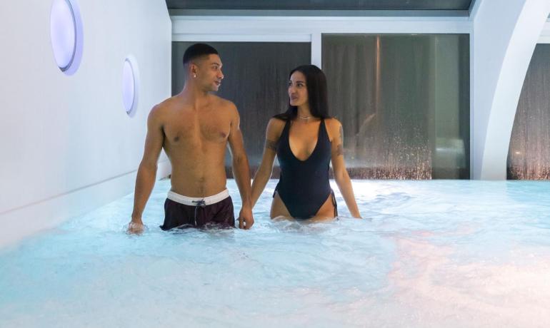 Coppia in piscina coperta, atmosfera rilassante.