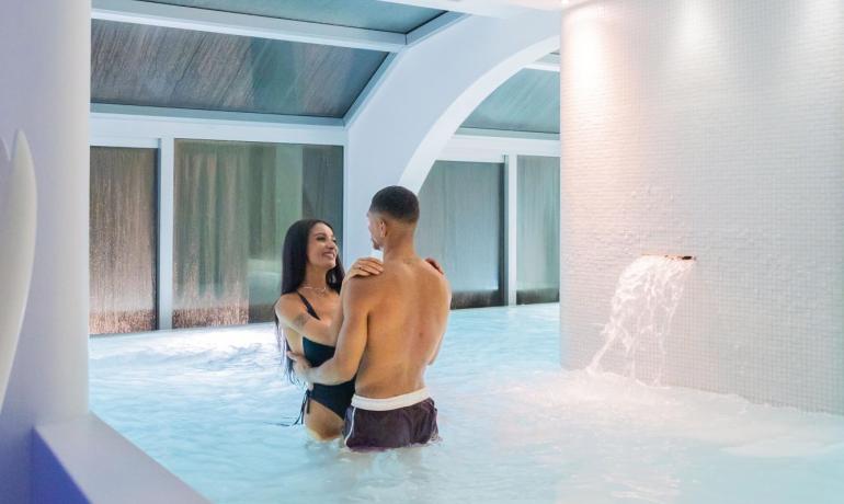 Happy couple in indoor pool with waterfall.