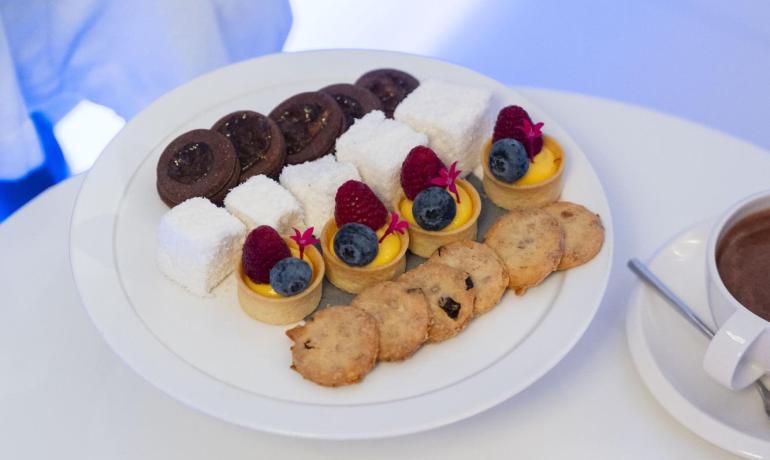 Assorted desserts and hot chocolate on a table with a candle.