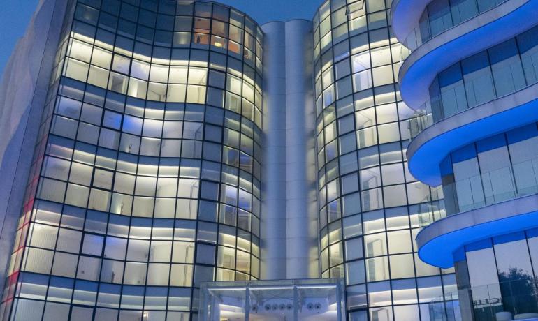 Modern building with glass facades and blue lights at night.