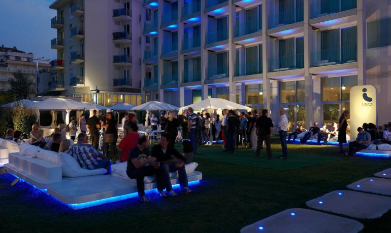 Lively evening party, blue lights, people socializing outdoors.