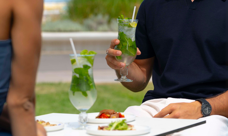 Zwei Personen stoßen mit erfrischenden Cocktails im Freien an, entspannte und gesellige Atmosphäre.